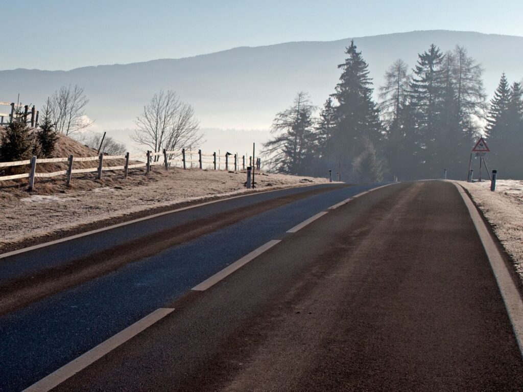 Una carretera y montaña nevados por el frío y con neblina