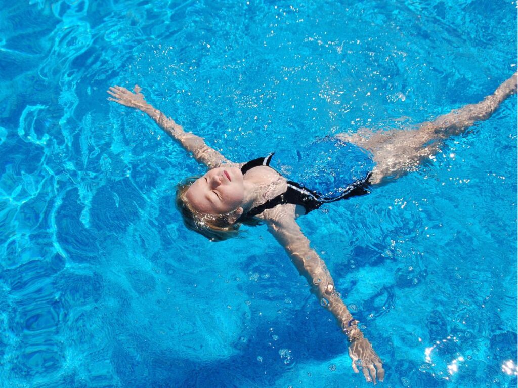 Niño flotando boca arriba, en una alberca 