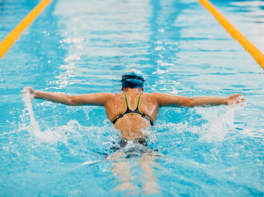 Mujer practicando estilos de natación con sus reglas, nadando mariposa