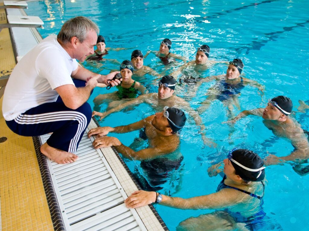 Entrenador enseñando a deportistas reglas de natación