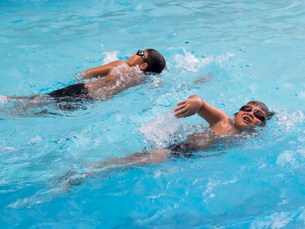 Niños nadando para hacer ejercicios mientas se protegen del sol